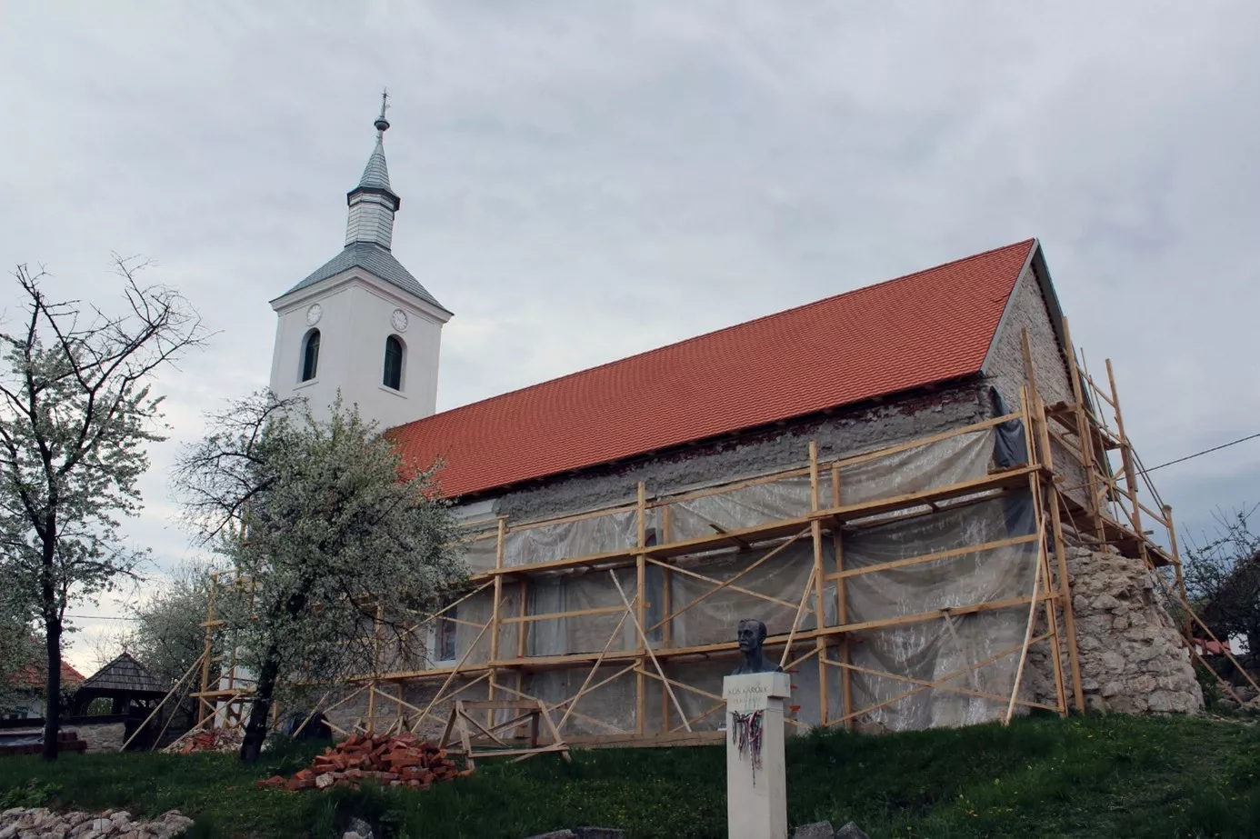 A sztánai református templom látképe, előtérben Kós Károly (1883–1977) mellszobra